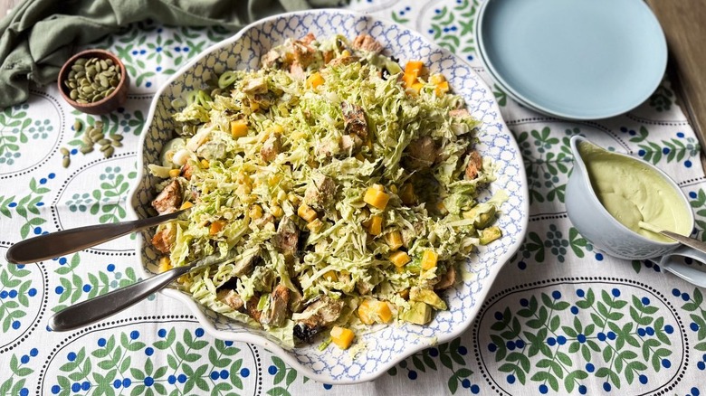 Chopped mango avocado chicken salad in serving bowl with avocado ranch dressing on the side