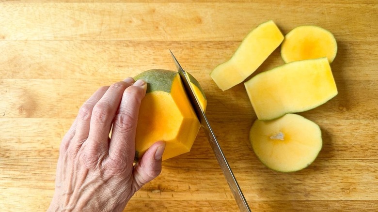 Cutting the peel off a mango on a cutting board