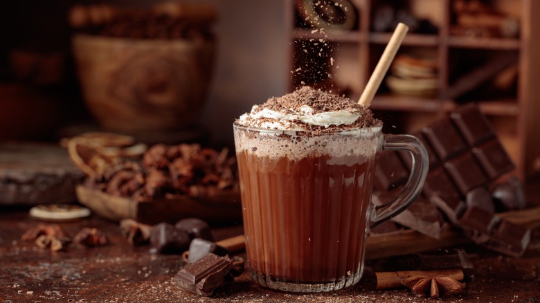 Hot chocolate is topped with whipped cream and chocolate shavings in a luxurious presentation.