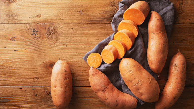 Heap of organic sweet potato or batata on wooden kitchen table top view.