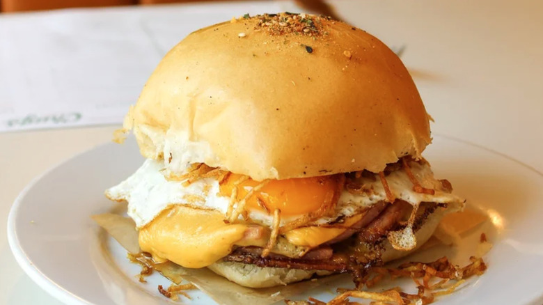 The breakfast sandwich from Chug's diner on a plate, with eggs, cheese, ham, and potatoes.