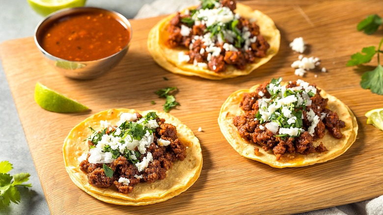 Flat layered corn tortillas with cooked chorizo, crumbled white cheese, and cilantro