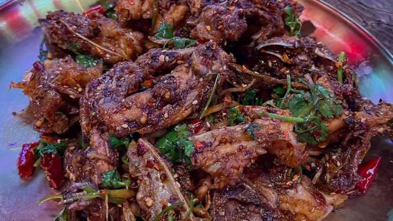 A crispy, meaty, and perfectly charred dish flowered with garnish and crushed pepper