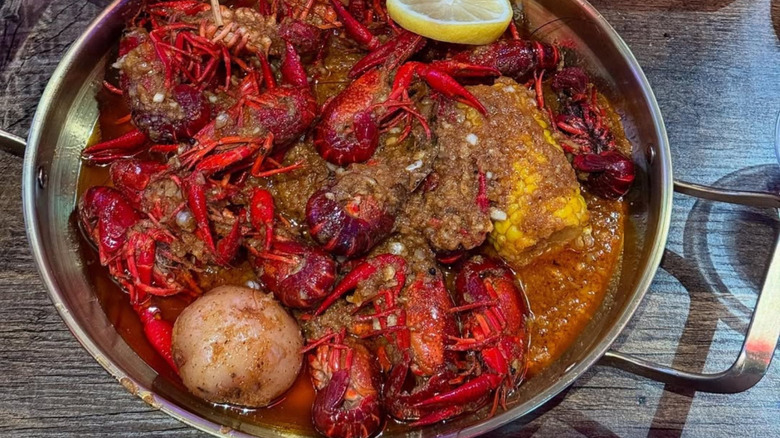 A close-up image of Gao's seafood boil in a steel bowl, looking saucy, flavorful, and loaded with ingredients