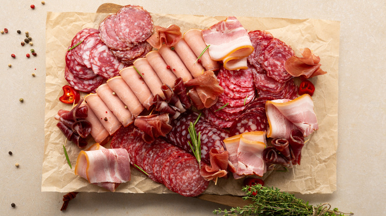 Slices of different deli meats lying on parchment paper