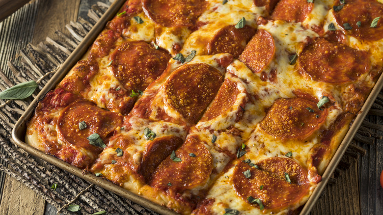 a pan of Sicilian pizza placed on a wooden board.