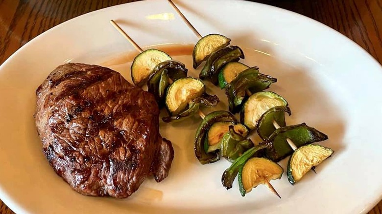 Steak and veggie kabobs on a white plate