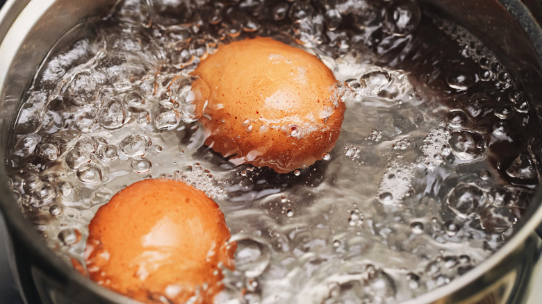 Brown eggs boiling in a pot of water