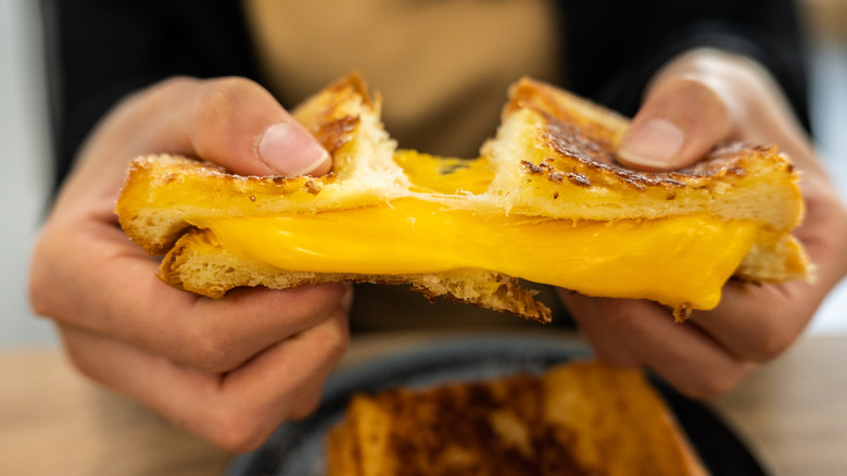 person tearing a grilled cheese sandwich