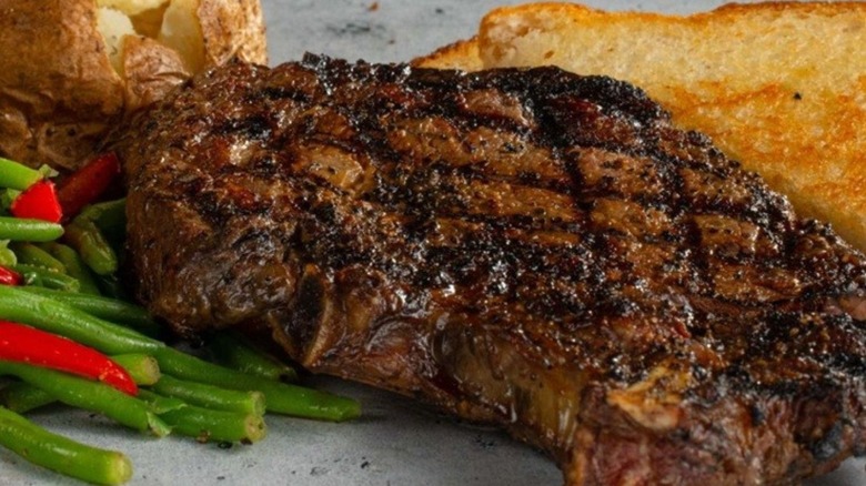 Grilled ribeye with veggies, toast, and potato.