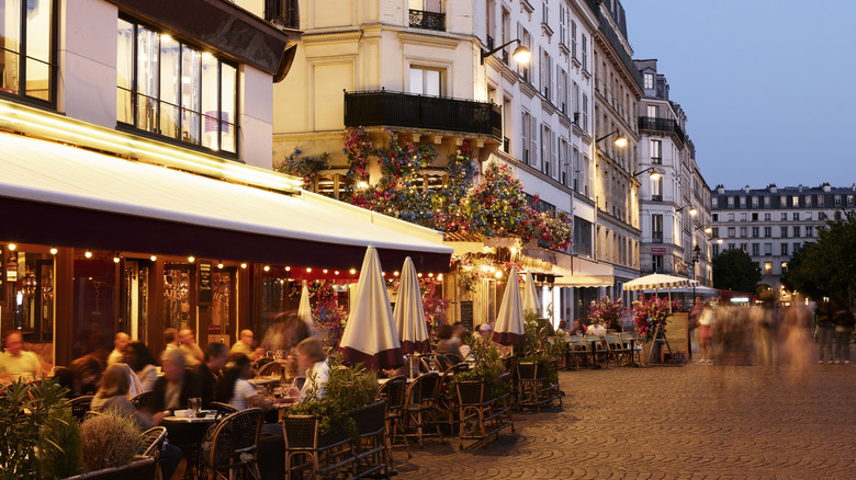 People dining outside at a busy restaurant in Paris