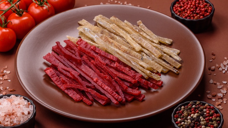 Shredded beef and chicken jerky on a brown plate surrounded by various ingredients