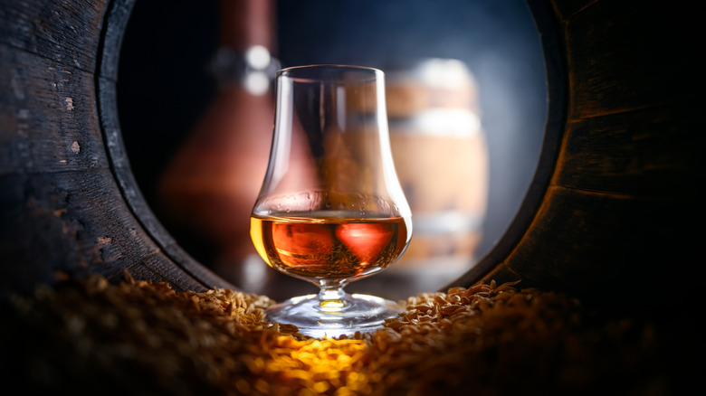 Tasting glass with whiskey inside a barrel
