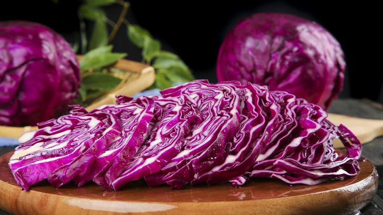 Slices of purple cabbage with two whole purple cabbages in the background