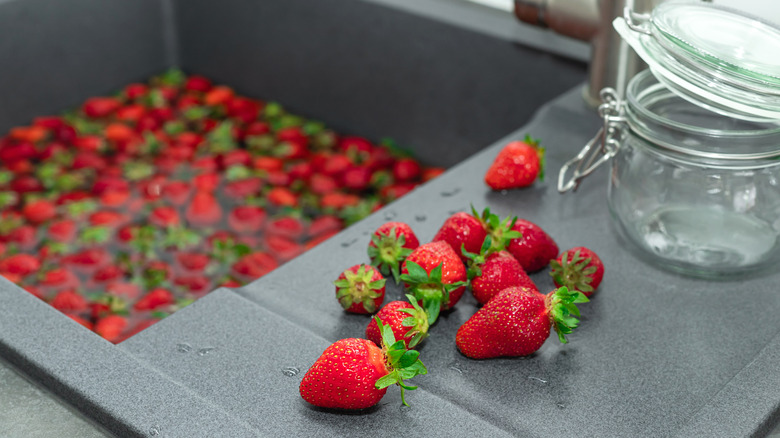 Strawberries being soaked in a farmhouse sink