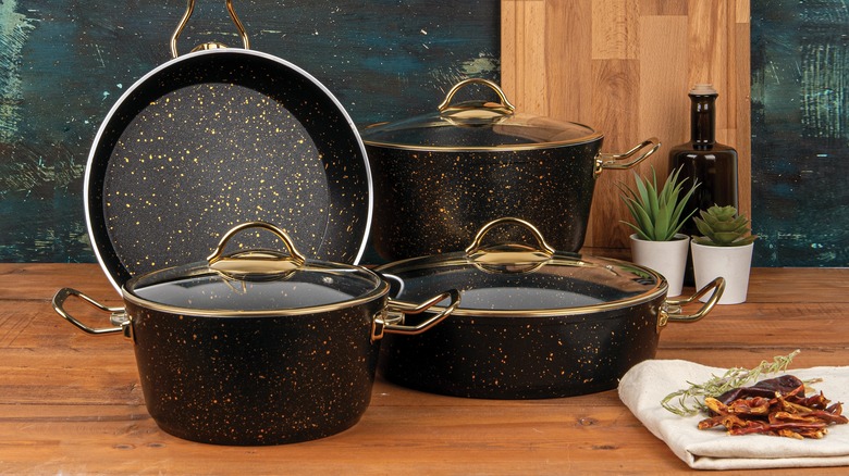 A set of black cookware displayed on a wooden table.