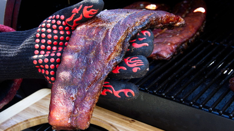 A gloved hand holds a pork rib, testing its bend