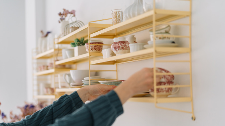 Hands putting dishes on wall rack