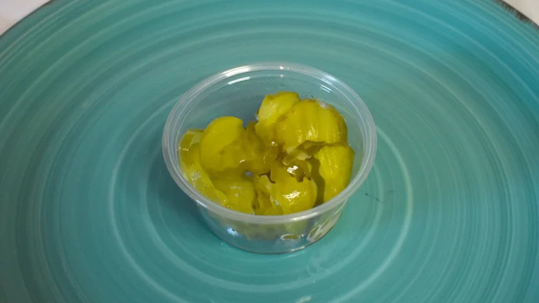 A small plastic cup filled with pickles from Braum's restaurant