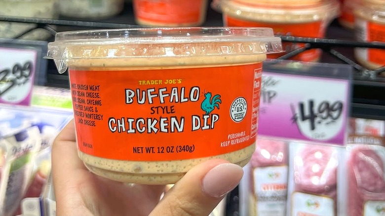 Hand holding a container of Trader Joe's Buffalo Chicken Dip in store