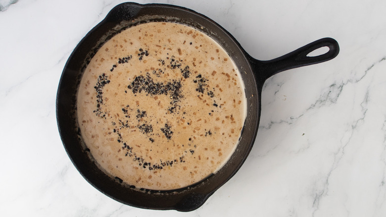 crushed pepper on top of a creamy brown sauce in a black frying pan