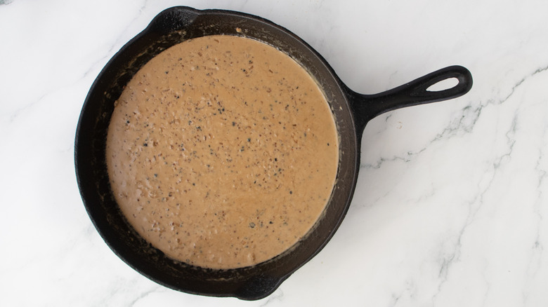 creamy brown sauce in a black frying pan