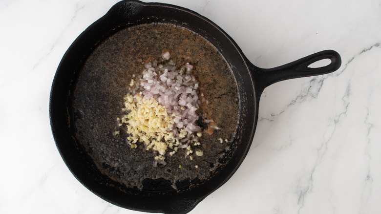 chopped garlic and shallots in a black frying pan