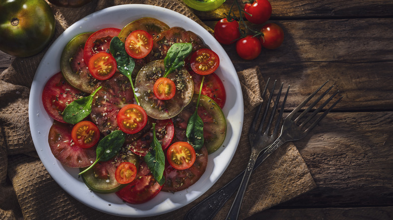fresh tomato salad on a plate with fresh herbs