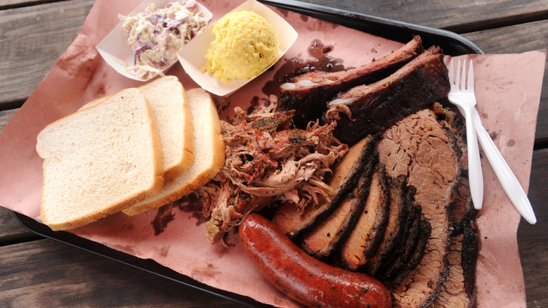 Serving of Texas BBQ on plastic platter atop wooden table.