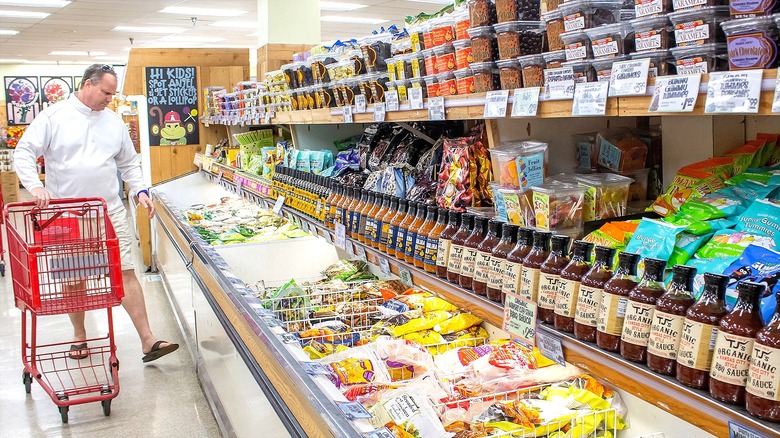 A man holding a red shopping cart, perusing the frozen section at Trader Joe's