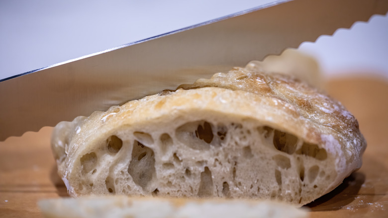 Serrated knife cutting through bread