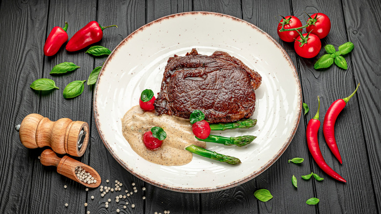 juicy seared steak on a plate with veggies and cream sauce