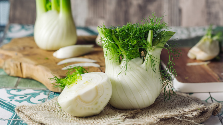 Raw fennel is halved on a cutting board