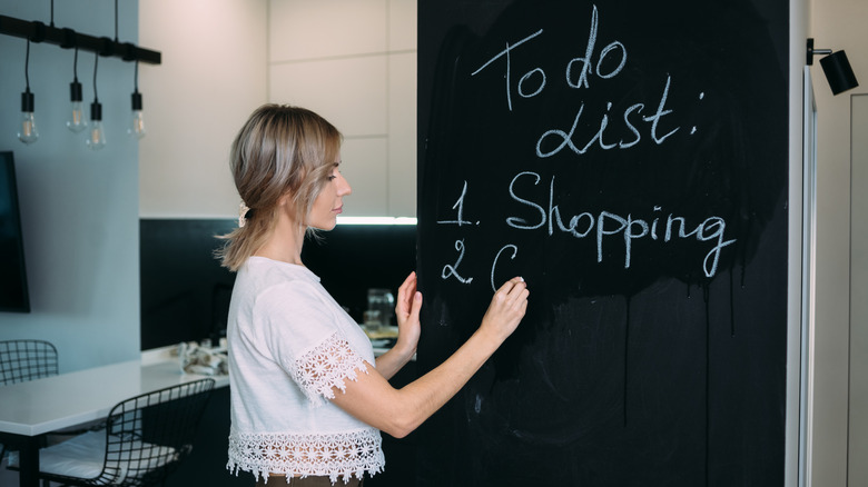 woman writing list on chalkboard kitchen