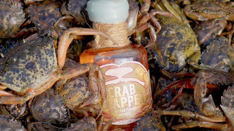 bottle of Crab Trapper Whiskey surrounded by green crabs