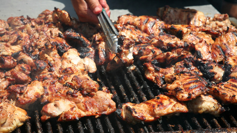 Many grilled chicken thighs on large grill grate