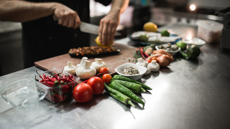 A chef slicing a lemon surrounded by fresh ingredients