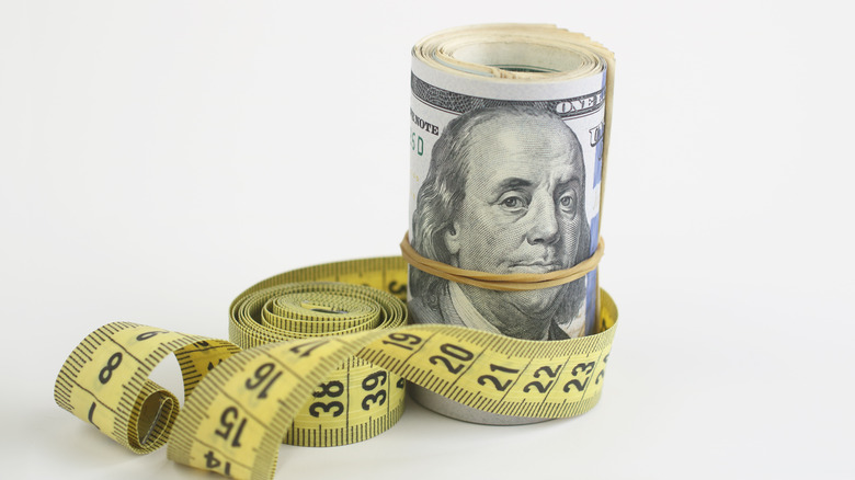 Measuring tape around dollar bills