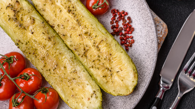 Delicious zucchini cut into two halves baked with salt, spices and herbs on a dark concrete background