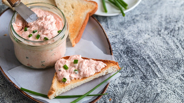 Smoked salmon dip in a small glass jar and on a toast point with chopped chives.