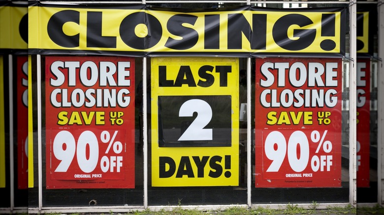Closing and sale signs outside of a liquidation store.