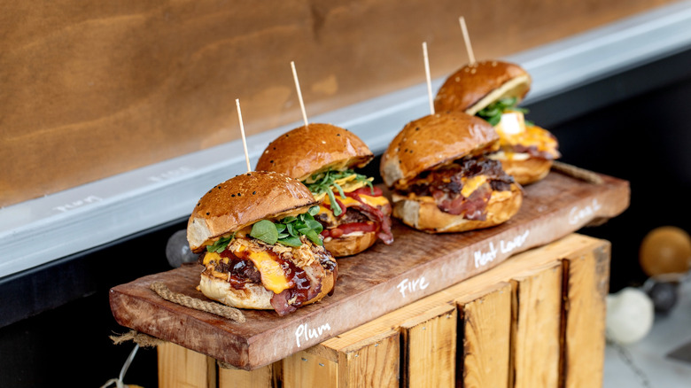 bacon cheeseburger sliders served on a wooden plank