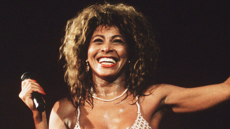 Tina Turner smiling and performing on stage