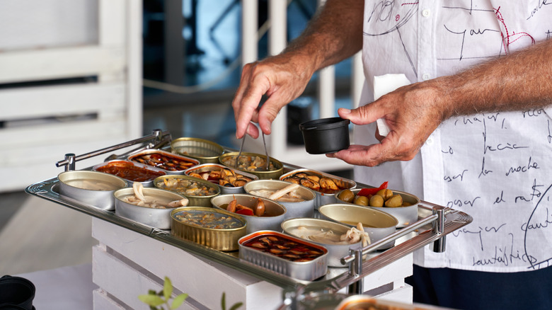 Person grabbing tinned seafood