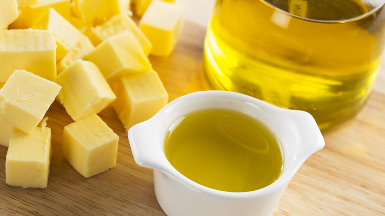 Cubes of butter and a small dish of oil on a wooden countertop