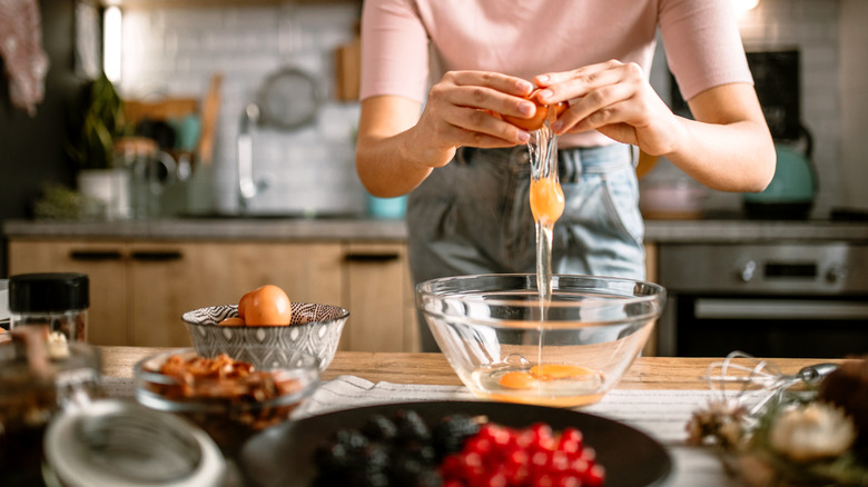Person cracking eggs into a bowl