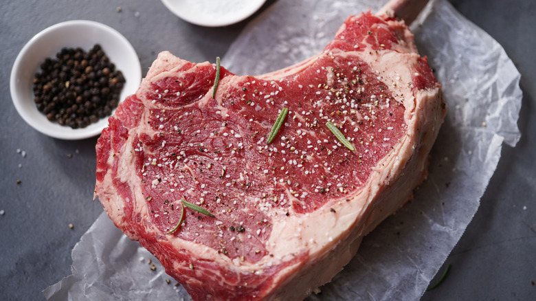 Seasoning a tomahawk steak with herbs