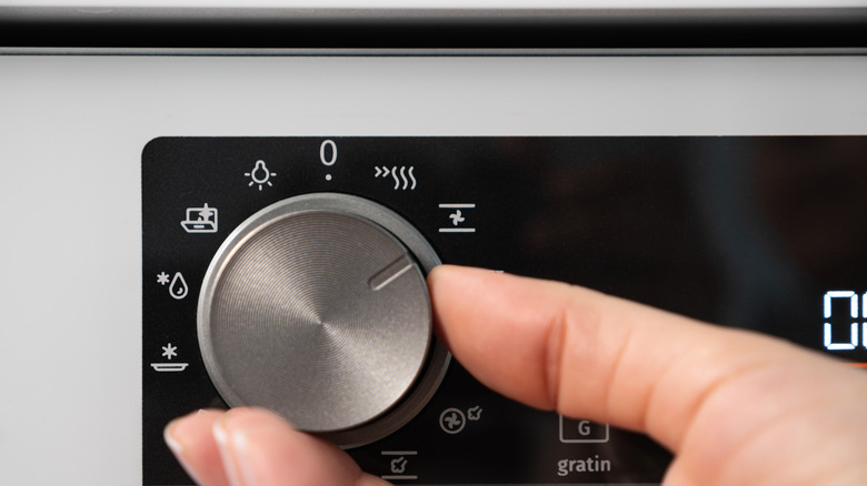 Person turning on a dial on a stove