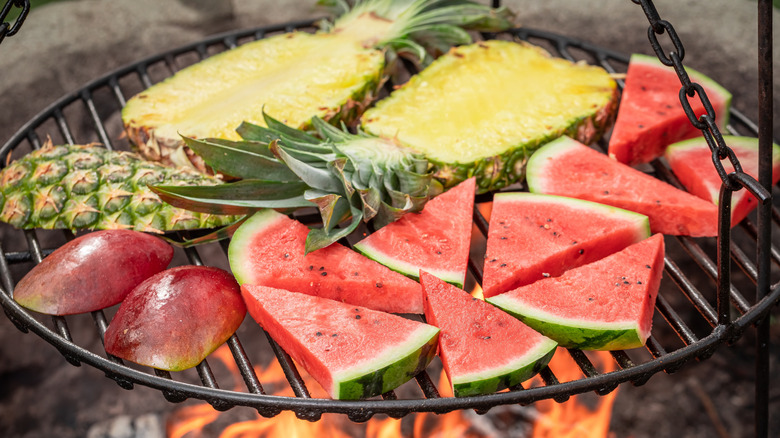 Watermelon, pineapple, and mango sit on a grill