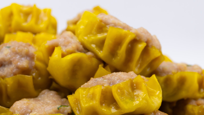 Yellow shumai wrappers around meaty filling.